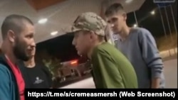 Qırımlı Dlâver Salimov (soldan) ve yaqarlıq stantsiyasınıñ hadimi Z işaretli kepkada. «Krımskiy SMERŞ» Telegram kanalı derc etken videodan, 2023 senesi avgust ayı
