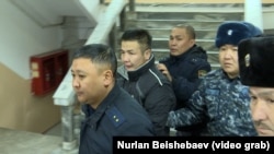 Укук коргоо органдарынын кызматкерлери Азамат Эстебесовду алып баратышат. Архив сүрөт. 