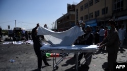 Afghan volunteers carry the bodies of victims at the scene of a suicide attack that targeted crowds of minority Shiite Hazaras during a demonstration at the in Kabul on July 23.