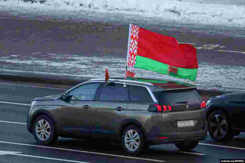 Каля парку Чалюскінцаў насупраць калёны аўтамабіляў з чырвона-зялёнымі сьцягамі зьявіўся невялікі «ланцуг салідарнасьці» зь бел-чырвона-белым сьцягам.