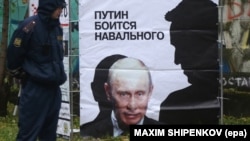 Росія. Поліцейський біля плакату із зображенням опозиційного політика та антикорупціонера Олексія Навального (праворуч) та президента Росії Володимира Путіна. Кіров, 16 жовтня 2013 року