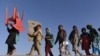 FILE: Afghan refugees, who have voluntarily returned from neighboring Pakistan with assistance from United Nation High Commissioner for Refugees (UNHCR) carry a chair and a board to attend an open air school outside their temporary shelters in the eastern Nangarhar Province.