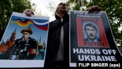 Демонстрант тримає антипутінські банери під час акції протесту проти агресії Росії щодо України перед посольством Росії в Чехії. Прага, 17 квітня 2014 року