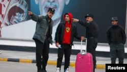 FILE: Afghan police officers talk with an Afghan after he was deported from Germany.