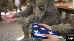 A U.S. soldier holds the national flag ahead of a handover ceremony at Leatherneck Camp in Lashkar Gah in Helmand, April 2017.