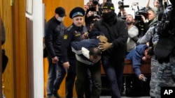 Шектүүлөрдүн бирин сот залынан алып чыгып бараткан учур.