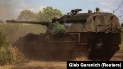 Українські військовослужбовці їдуть на німецькій САУ Panzerhaubitze 2000 із написом «Доброго вечора, ми з України!» поблизу передової на Донбасі, липень, 2022 року