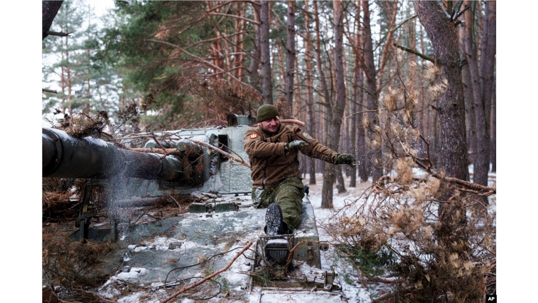 Un soldat cu dizabilități din Brigada 127 din Ucraina, care și-a pierdut un picior în luptă în 2015, își scoate camuflajul de pe obuzierul autopropulsat. 10 februarie 2025.