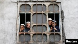 Afghan students from a religious school look on from a window of their school in Kabul on October 5.