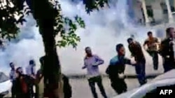 Antigovernment protesters run for cover from tear gas fired by security forces in the capital, Damascus, on April 29.