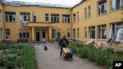 Офіцер поліції тягне генератор, рятуючи цінне майно сільської адміністрації у Вільчі поблизу Вовчанська, Україна, 12 травня 2024 року. Фото ілюстративне