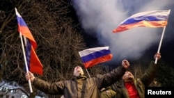 Представники угруповання «ДНР» у Донецьку, в однаковій формі із прапорами Росії, вітають оголошене президентом Росії Володимиром Путіним «визнання республік Донбасу»